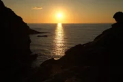 Sonnenuntergang an der Felsenk&uuml;ste Sardinien. Wenn bei Sardinien die rote Sonne im Meer versinkt.