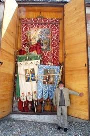 Sepp Forcher vor dem Fahnenkasten in Weissenbach/Ahrntal. Weil die Kirche des Ortes zu klein ist, werden die Fahnen aller Vereine in einem eigenen Fahnenkasten aufbewahrt.