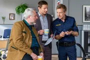 Polizeihauptmeister Mohr (Max M&uuml;ller, r.) informiert die Kommissare Stadler (Dieter Fischer, l.) und Hansen (Igor Jeftić, M.) &uuml;ber die neuen Rechercheergebnisse.