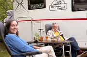 Petra (l) und R&uuml;diger Erbsl&ouml;h vor ihrem Camper, den sie liebevoll &bdquo;Olaf&ldquo; genannt haben.