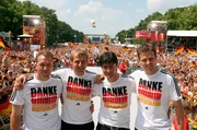 Torwart-Trainer Andreas Koepke (l-r), der damalige Bundestrainer J&uuml;rgen Klinsmann, sein damaliger Co-Trainer Joachim L&ouml;w und Team-Manager Oliver Bierhoff stehen auf der Fan-Meile am Brandenburger Tor zusammen.