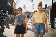 Norah (Deleila Piasko, vorne l.) besucht mit ihrer Nachbarin und Freundin Theresa (Luisa-C&eacute;line Gaffron, vorne r.) den Prater: Hier soll sie laut der Prophezeiung am 13. August Arthur Grimm t&ouml;ten.
