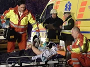 Dr. Brentano (Thomas Koch, links) wird mit dem Notarztwagen zu einem Autounfall gerufen. Erst als Prof. Simoni an der Unfallstelle ankommt, stellt sich heraus, dass der Verletzte Prof. Hanno Hinze (Karl Kranzkowski, liegend) ist. Rechts: 3 Komparsen.