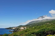 Der Ort S&atilde;o Jo&atilde;o an der S&uuml;dk&uuml;ste Picos. Im Hintergrund ist der Vulkan Ponta do Pico zu sehen.