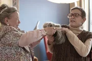 Christel (Ursula Werner) hat gro&szlig;en Spa&szlig; daran, Helene (Katharina Thalbach) f&uuml;r die Geld&uuml;bergabe an den Betr&uuml;ger zu einem unbedarften Hascherl zu verkleiden.