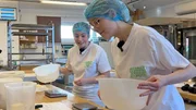 B&auml;ckereilehrling Isabella und Lena schauen auf Lenas misslungenen Teig.