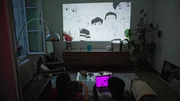 &Eacute;milie Tronche und Oph&eacute;lie Lepert schauen sich gemeinsam Zeichentrickfilme &uuml;ber den Beamer im Wohnzimmer an.