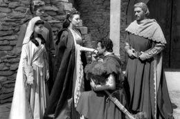 Sir Lancelot (Robert Taylor, 2.v.r.) k&uuml;sst K&ouml;nigin Guinevere (Ava Gardner, Mi.) die Hand. Seine Frau Elaine (Maureen Swanson, li.), Percival (Gabriel Woolf, 2.v.l.) und K&ouml;nig Artus (Mel Ferrer, re.) wohnen der Szene bei.