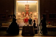Szene aus &bdquo;Il Gattopardo&ldquo; am Schauspielhaus Z&uuml;rich: Vor einem reich dekorierten Hausaltar versammelt sich die Familie Salina rund um eine gedeckte Tafel, im Hintergrund stehend Markus Scheumann als Don Fabrizio.