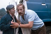 Bei einem Auffahrunfall in Prag hat Beifahrer Orje (Fred Delmare, l.) seine Mundharmonika verschluckt. Nun braucht Fred (Manfred Krug) Ersatz.