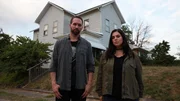 Hosts Nick Groff and Katrina Weidman stand in yard with Monroe Demon House in hill behind them.