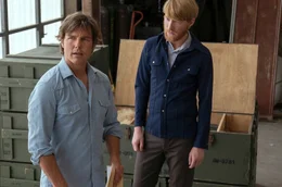 Barry Seal ( Tom Cruise, l.) und Monty Schafer (Domhnall Gleeson), sein Verbindungsmann zur CIA, mit einer Waffenlieferung f&uuml;r die Contras im Hintergrund.