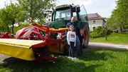 Bernhard Hauer (Mitte) mit zwei seiner vier Kinder und seinem Traktor vor dem familieneigenen Vierkanter.
