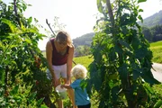 Agnes Penner (links) und ihr kleiner Sohn ernten Gem&uuml;se im eigenen Bauerngarten