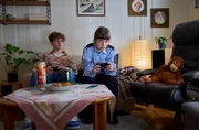 Otmar (Bennik Gehring, l.) und Jenny (Eva B&uuml;hnen, r.) verbringen den Abend zusammen. Sie spielen Videospiele und essen Chips.