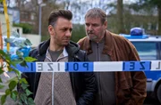 Mehmet (Cem Ali G&uuml;ltekin, l.) und Arthur (Felix V&ouml;rtler, r.) stehen hinter der Polizeiabsperrung des Tatorts. Die beiden haben in Jennys Vorgarten eine Leiche entdeckt.
