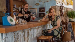 Renate (Deborah Kaufmann) l&auml;sst sich von Nikos (Angelos Andriopoulos) einen Drink machen.
