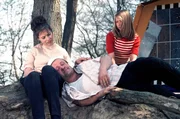 Familie sitzt ersch&ouml;pft an einem Baum.