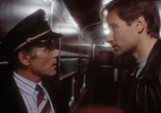 Mulder (David Duchovny, r.) will sich von eine Zugschaffner (l.) den Regierungswaggon öffnen lassen, in dem er einen Außerirdischen vermutet. Mulder (David Duchovny, r.) will sich von eine Zugschaffner (l.) den Regierungswaggon öffnen lassen, in dem er einen Außerirdischen vermutet.