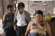 Die Stadt wird von Banden beherrscht. Der einzige Ort, der vor den Gangstern Zuflucht bietet, ist die Siedlung "Residenz Schweinestall". Dies &auml;ndert sich erst, als der M&ouml;chtegern-Ganove Sing (Stephen Chow, M.) und sein Kumpel (Lam Tze Chung, r.) dieses Viertel aufsuchen und dort versuchen, einige der wehrlosen Anwohner zu erpressen ...