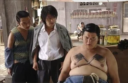 Die Stadt wird von Banden beherrscht. Der einzige Ort, der vor den Gangstern Zuflucht bietet, ist die Siedlung "Residenz Schweinestall". Dies &auml;ndert sich erst, als der M&ouml;chtegern-Ganove Sing (Stephen Chow, M.) und sein Kumpel (Lam Tze Chung, r.) dieses Viertel aufsuchen und dort versuchen, einige der wehrlosen Anwohner zu erpressen ...