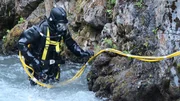 Dustin Hurt in full dive gear in shallow edge of creek.
