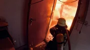 Feuerwehrmann der Berufsfeuerwehr Augsburg, der in ein brennendes Geb&auml;ude hinein l&ouml;scht.