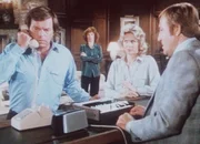 Jonathan Hart telefoniert mit dem Entf&uuml;hrer seines angeblichen Sohnes, w&auml;hrend dessen Mutter gespannt mith&ouml;rt und ein Polizist das Gespr&auml;ch mitschneidet ...