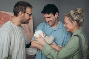 Anna (Anna Schudt, r.) lernt das Baby von Valentin (Knut Berger, l.) und Nic (Fabian Stumm, M.) kennen. Die beiden sind mithilfe einer Leihmutter Eltern geworden und sorgen sich jetzt darum, ob ihr Baby seine Bauch-Mama vermisst. Anna gibt den beiden Starthilfe in Sachen Bauchgef&uuml;hl.