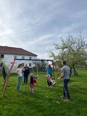 Die gesamte Bauernfamilie verbringt gemeinsam Zeit mit den Kindern auf der Schaukel.