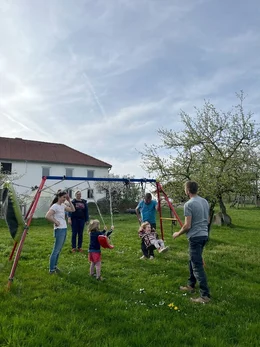 Die gesamte Bauernfamilie verbringt gemeinsam Zeit mit den Kindern auf der Schaukel.