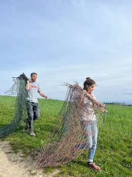 Der/die Landwirt/in bauen einen neuen Zaun um ihre Felder auf.