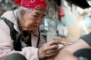 Die um 1917 geborene Whang Od ist beim T&auml;towieren mit dem Dorn eines Zitrusbaums hochkonzentriert: Sie beherrscht als eine von wenigen die uralte T&auml;towiertechnik Batok.