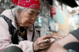 Die um 1917 geborene Whang Od ist beim T&auml;towieren mit dem Dorn eines Zitrusbaums hochkonzentriert: Sie beherrscht als eine von wenigen die uralte T&auml;towiertechnik Batok.