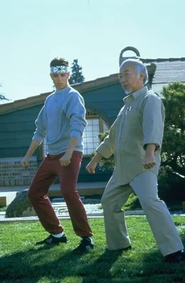 Daniel LaRusso (Ralph Macchio, l.) wird zu einem Kampf herausgefordert - doch sein Meister Mr. Miyagi (Pat Morita) will ihn nicht unterst&uuml;tzen.