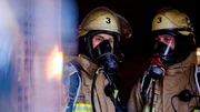 Zwei Feuerwehrmänner tragen Atemschutzmasken und Helme, die mit einer "3" gekennzeichnet sind. Starke Verrauchung, Ursache unklar – Einsatz wegen eines Kaminbrands im Entstehungsstadium. Zwei Feuerwehrmänner tragen Atemschutzmasken und Helme, die mit einer "3" gekennzeichnet sind. Starke Verrauchung, Ursache unklar – Einsatz wegen eines Kaminbrands im Entstehungsstadium.