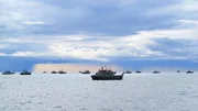 A storm brewing with ships in the bay.