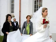 Vor der Kirche haben die Brautjungfern Elena Eichhorn (Cheryl Shepard, links) und Pia Heilmann (Hendrikje Fitz, 2. von rechts) beide H&auml;nde voll zu tun, Sarah Marquardt (Alexa Maria Surholt) zu beruhigen. Aufgeregt l&auml;uft sie vor der Kirche hin und her. Erst als Prof. Simoni (Dieter Bellmann, hinten) ein Machtwort spricht, l&auml;sst sie sich in die Kirche f&uuml;hren.