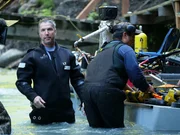 Dustin Hurt wearing his dive suit and Carlos working on the dredge.