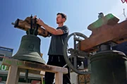 Glockenspezialist Simon Westermann montiert eine Glocke an das Joch.