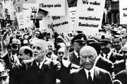 Charles de Gaulle (vorn, l) und Bundeskanzler Konrad Adenauer (vorn, r) in der Menschenmenge. Im Hintergrund Plakate mit Schriftzug "Vive l'Europe unie" "Wir wollen den europ&auml;ischen Bundesstaat" Gestenreich bedankt sich Frankreichs Staatspr&auml;sident Charles de Gaulle (l.) (Archivfoto, 30.04.1962)