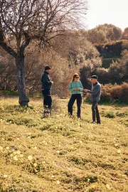 Federica Salvo, die Leiterin von Kolymbethra (Mitte), f&uuml;hrt Stanley Tucci (rechts) durch den weitl&auml;ufigen Garten, wo er auf Rino Frenda (links) trifft, der die Mandelb&auml;ume aufmerksam im Auge beh&auml;lt.