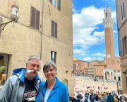 Petra (65) und R&uuml;diger (66) Erbsl&ouml;h in den Gassen von Siena mit dem Piazza del Campo und dem Palazzo Pubblico mit dem Torre del Mangia im Hintergrund.