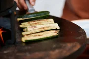 Die Zucchini werden auf dem Rundgrill gewendet. Die Zucchini werden auf dem Rundgrill gewendet.