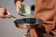 Kreuzkrümmel wird in eine Pfanne zum Anrösten hinzugegeben. Kreuzkrümmel wird in eine Pfanne zum Anrösten hinzugegeben.