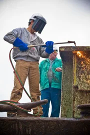 Host Mike Rowe uses torch to cut barge. At Cash's Scrap Metal, St. Louis, Missouri.