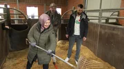 Bewegung, Entspannung und Spa&szlig; kombinieren! Wie das geht, zeigen Doc Esser (M) und Sportwissenschaftler Marwin Isenberg (r) der Dreifachmama Hatice aus Solingen beim Ausmisten des Pferdestalls.