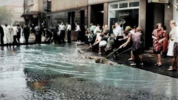 Der Film blickt auf die dramatischen Ereignisse im Juli 1965 zur&uuml;ck, als Ostwestfalen-Lippe von der schwersten Hochwasserkatastrophen der Nachkriegszeit heimgesucht wurde. Auch Teile von Niedersachsen, Hessen und der damaligen DDR wurden &uuml;berflutet. Besonders hart traf das Hochwasser das Dorf Etteln s&uuml;dlich von Paderborn. Wegen seiner Tallage lief das Dorf voll wie eine Wanne, Menschen k&auml;mpften ums &Uuml;berleben, w&auml;hrend die Helfer fieberhaft und oft vergeblich versuchten, die Eingeschlossenen zu retten. - Paderborn,  Die Gesch&auml;ftsleute in der Giersstr. versuchen mit vereinten Kr&auml;ften das Wasser aus den L&auml;den herauszuhalten.(Foto nachcoloriert mit KI)