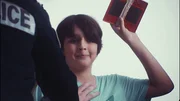 Geschafft! Von einem Polizisten (Alex Olliet) in Obhut genommen, zeigt Matthias (Alexandre Pagani) seinem Vater stolz, dass er ein schwieriges Level des Videospiels bew&auml;ltigt hat.
