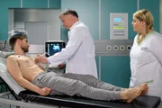 Schwester Miriam (Christina Petersen, rechts) hat John Neyers (Ren&eacute; Erler, links) bewusstlos in seinem Zimmer gefunden. Beim Ultraschall stellt Dr. Roland Heilmann (Thomas R&uuml;hmann) fest, dass Johns Herz sehr vergr&ouml;&szlig;ert ist. Das k&ouml;nnte aber auch mit Johns jahrelangem, intensivem Triathlon-Training zusammenh&auml;ngen. Rolands Frage, ob John schon mal &auml;hnliche Symptome hatte, verneint der Ex-Profisportler.